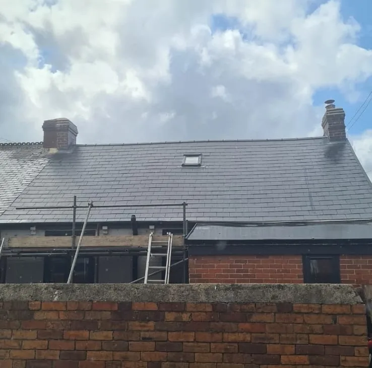 Completed re-roof on a terraced house with scaffolding and ladders