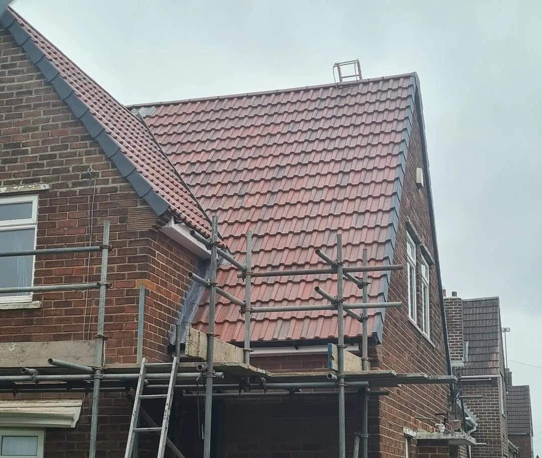 Re-roof in red tiles on a two-storey house with scaffolding around the roof