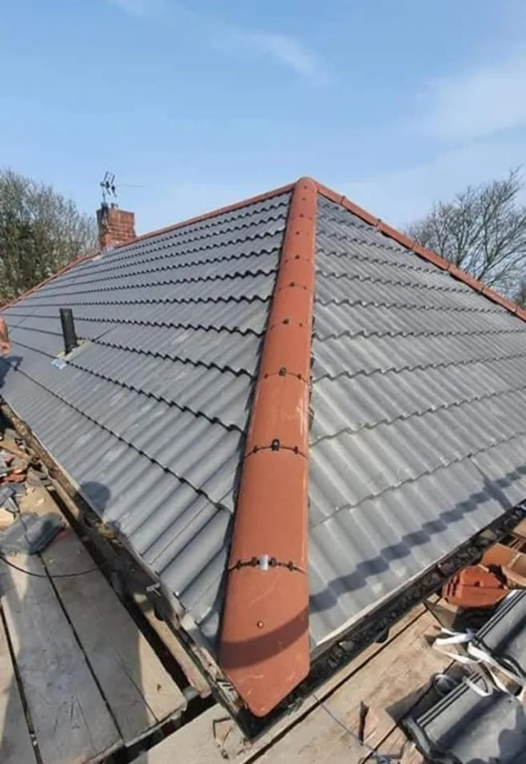 Dry hip and ridge with terracotta caps on a grey tiled roof