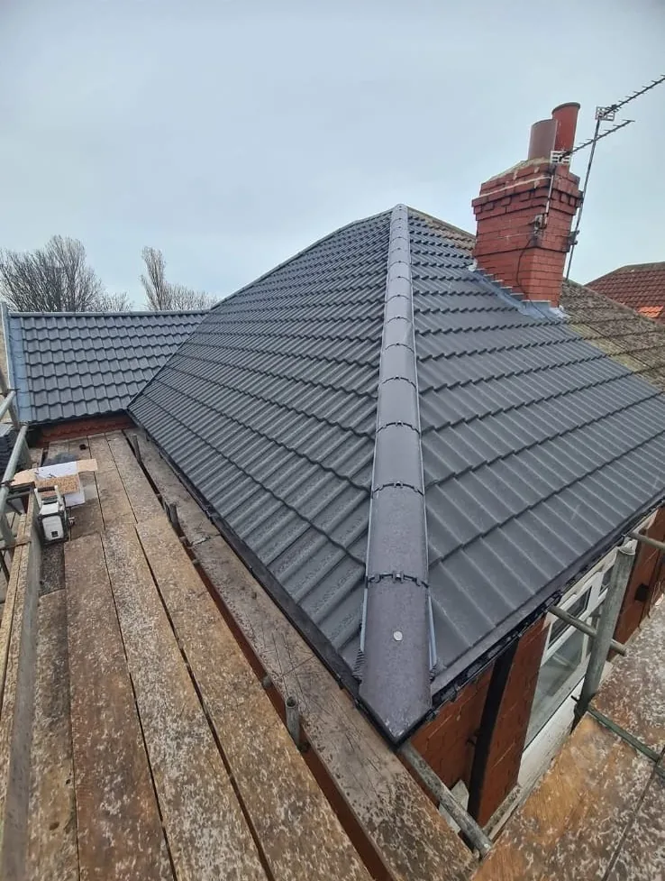 Completed re-roof with new grey concrete tiles and dry ridge on a hipped bungalow roof